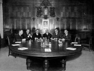 Das Foto zeigt den Vorstand der Dresdner Bank ca. 1937 unter einem Hitler-Portrait. Außen sitzen die beiden SS-Ehrenoffiziere Emil Meyer (links) und Karl Rasche (rechts).